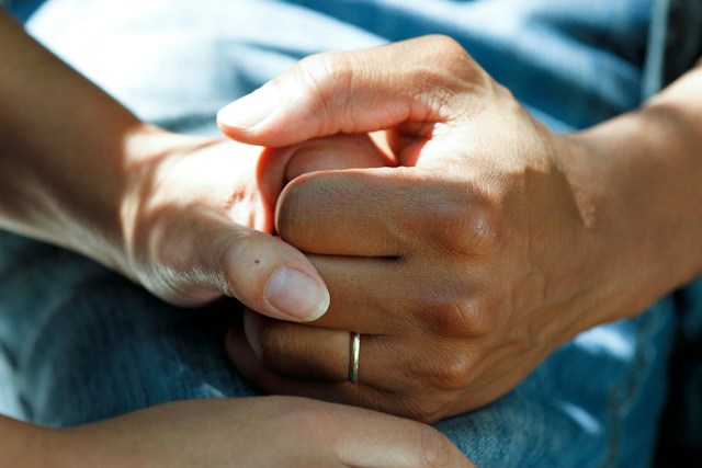 A caregiver holding the hand of a patient.