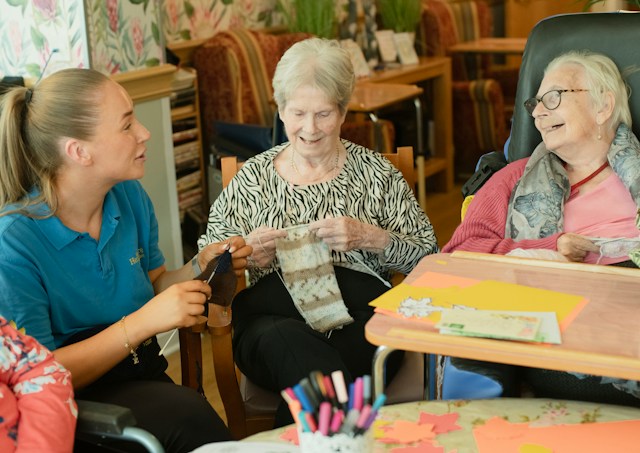 Three women bond and chat over textile arts.